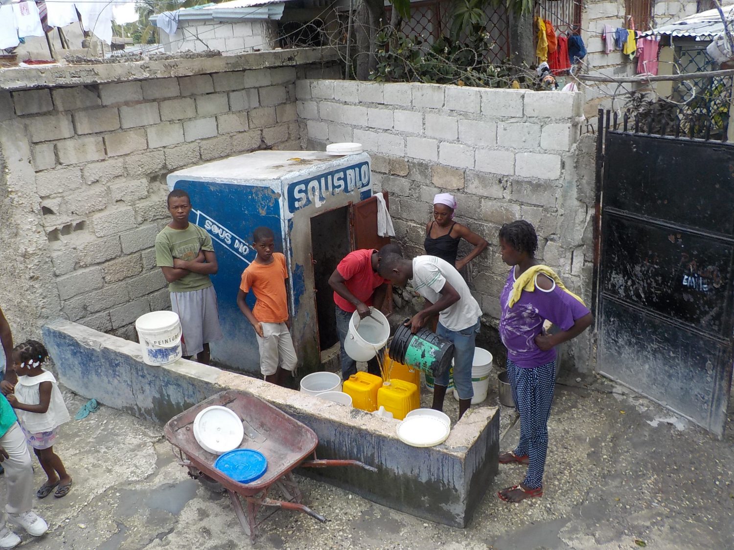 People queued at water pump with buckets